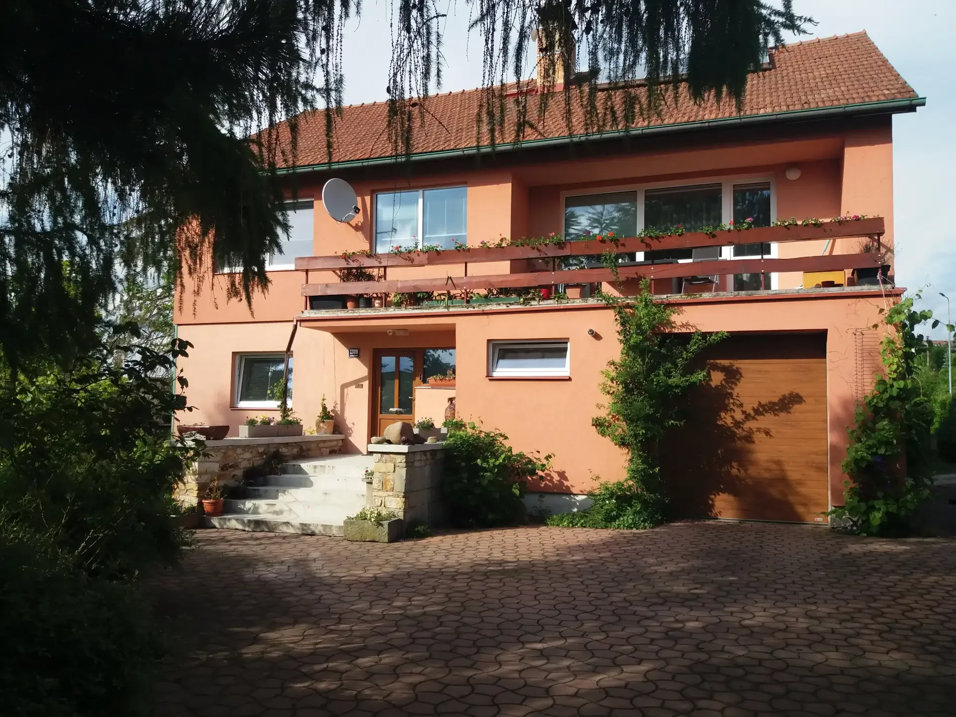 Rodinný dům s terakotovou fasádou, balkonem, garáží a příjezdovou cestou