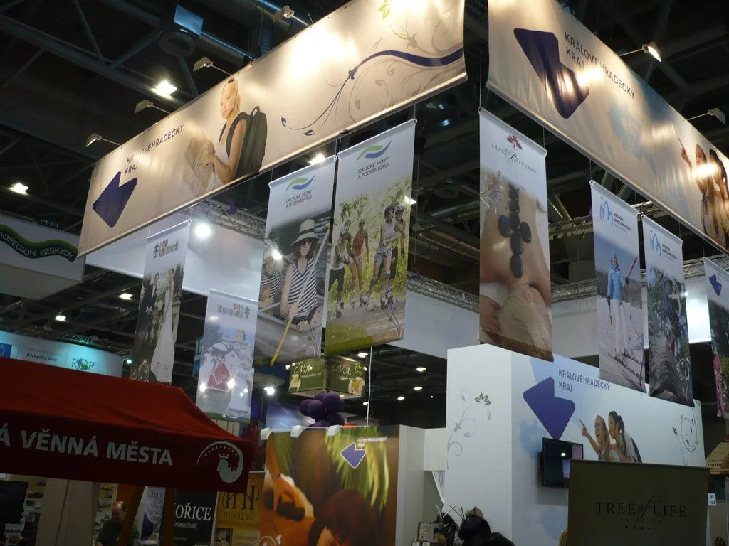 Zavěšené reklamní bannery turistických regionů pod stropem výstavní haly