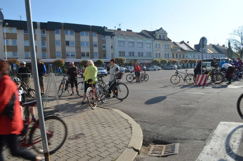 Cyklisté s koly na náměstí v Kostelci nad Orlicí před historickými domy
