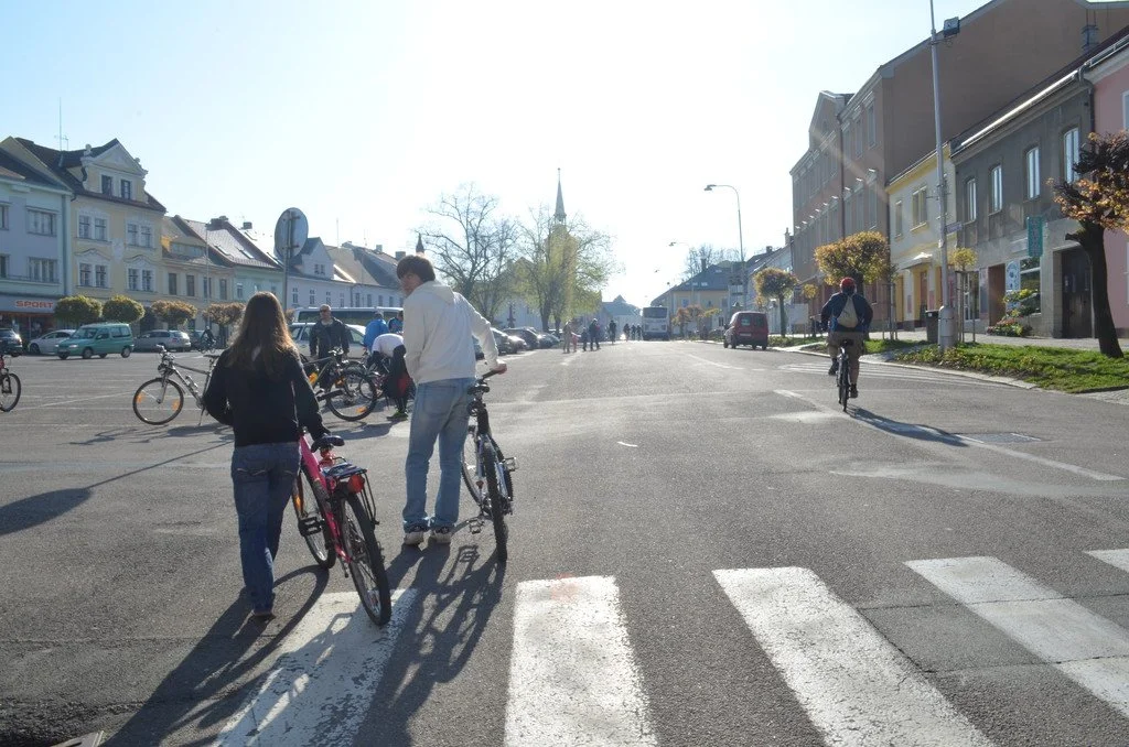 Lidé vedou kola přes přechod pro chodce v centru města