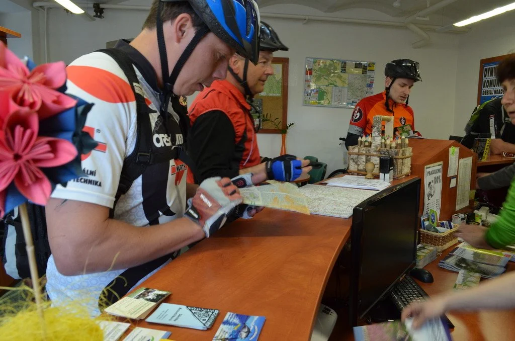 Cyklisté v přilbách u přepážky informačního centra