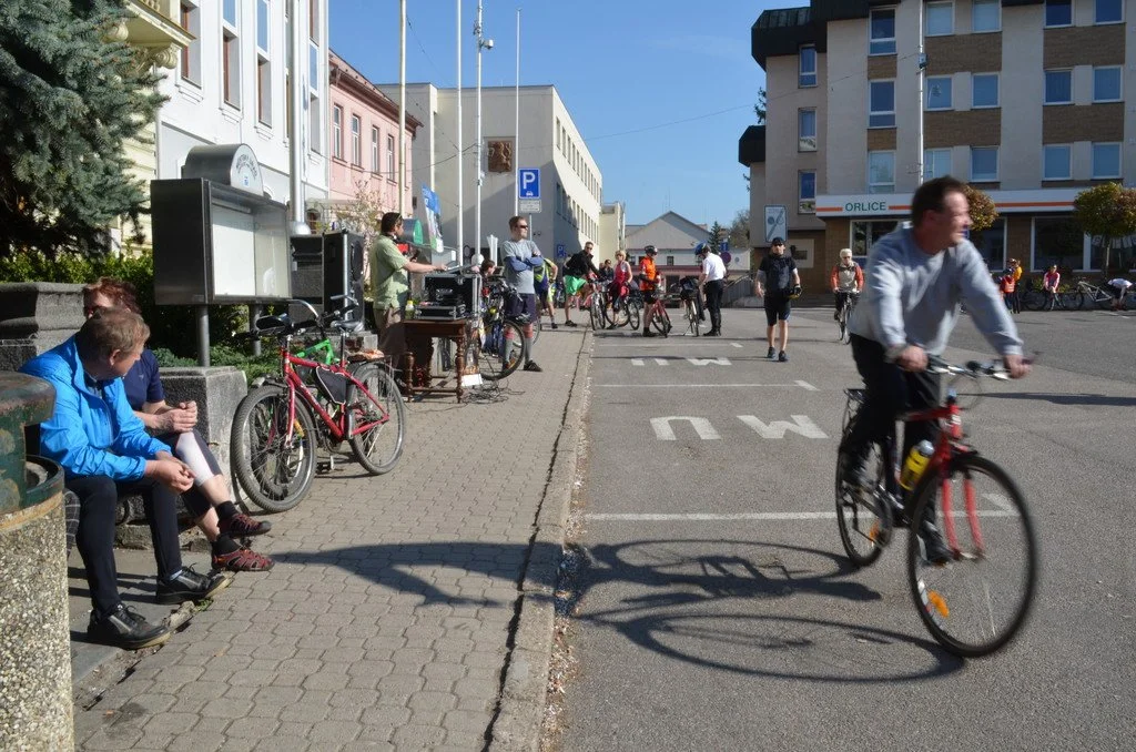 Cyklisté a chodci na ulici s ozvučovací aparaturou