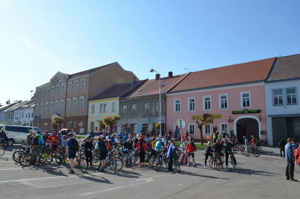 Velká skupina cyklistů na městském náměstí s historickými domy