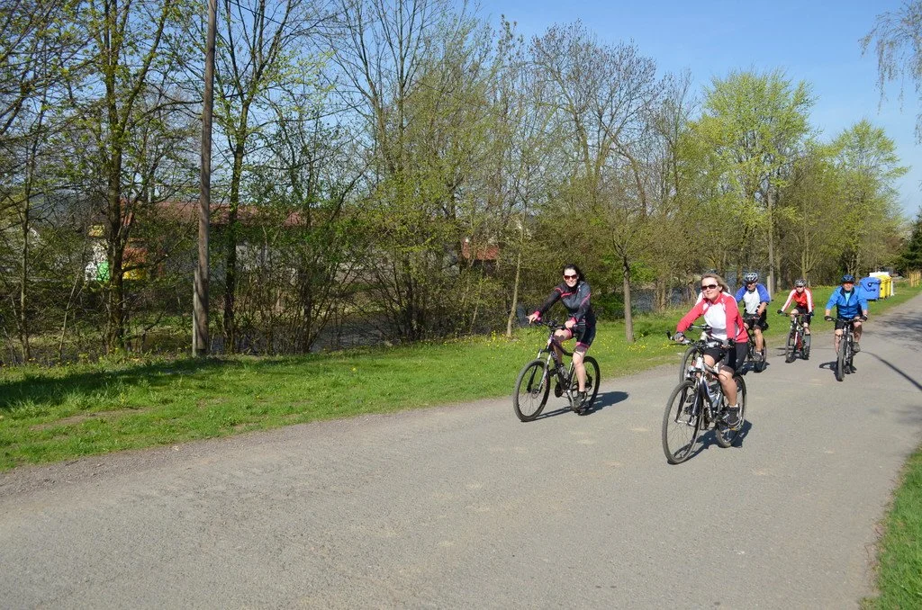 Skupina cyklistů jede po stezce podél řeky
