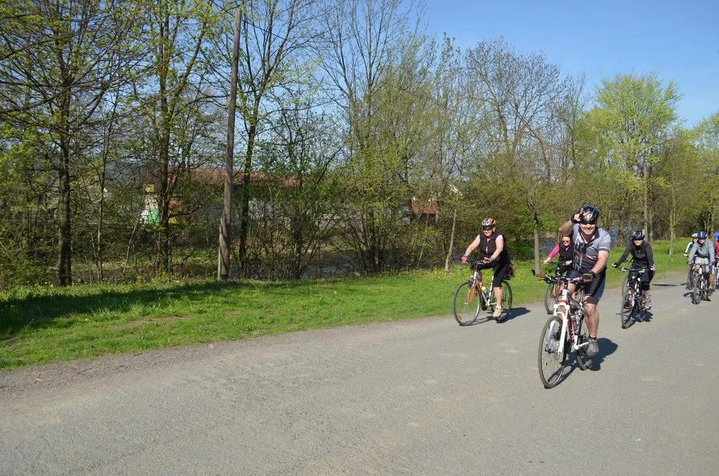 Skupina cyklistů jede po cyklostezce podél zeleně