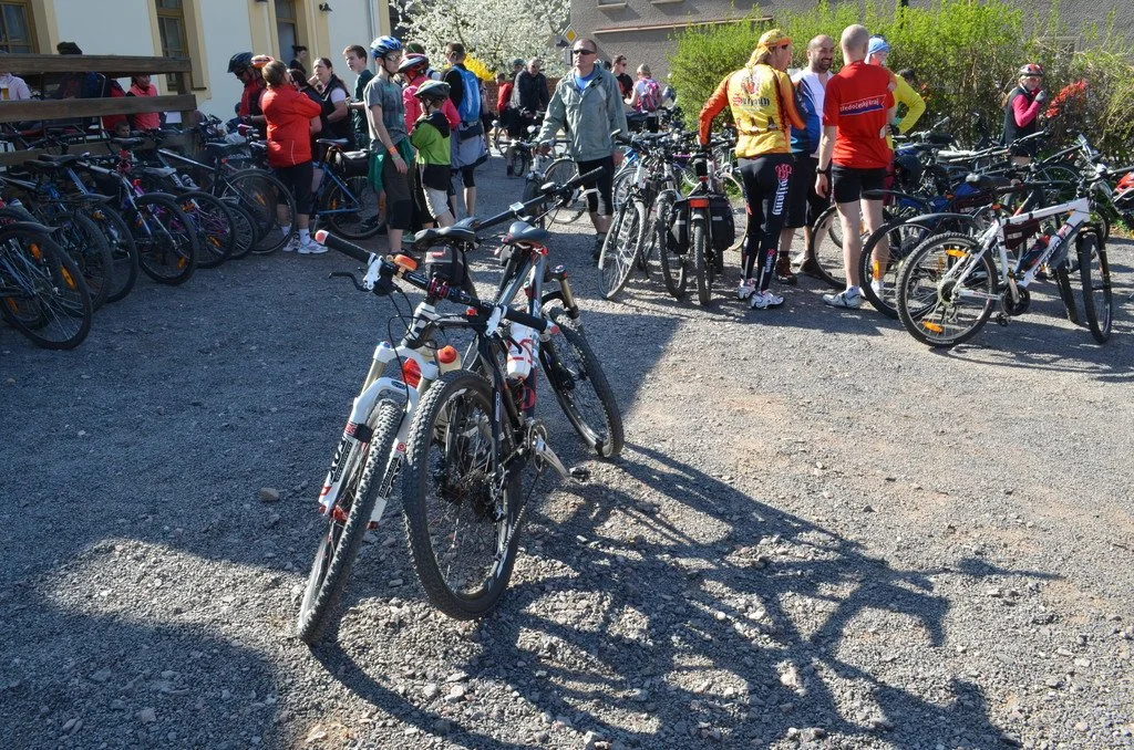 Cyklisté s koly odpočívají u budovy s kvetoucím stromem