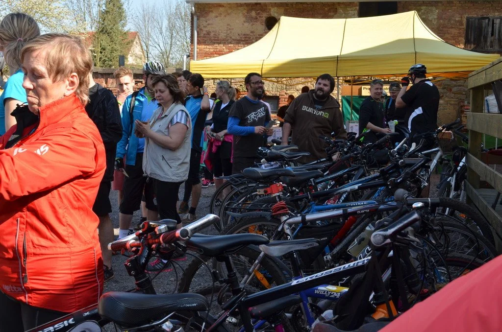 Cyklisté se shromažďují pod stanem u cihlové budovy