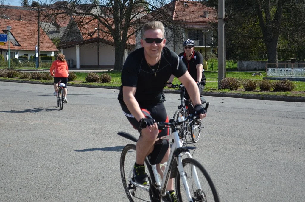 Usmívající se cyklista projíždí městskou ulicí