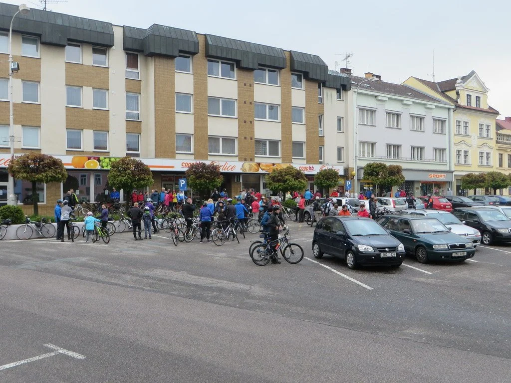 Cyklisté s koly před obchody na náměstí v Kostelci nad Orlicí