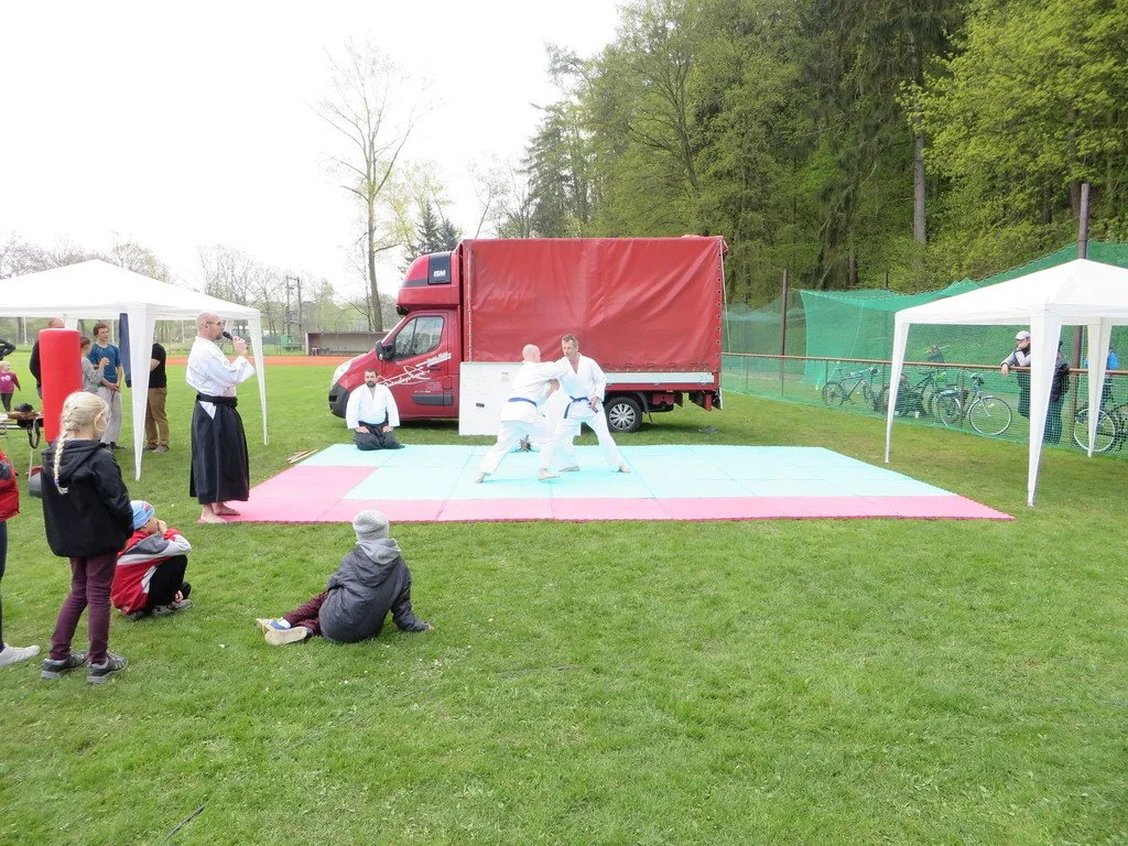 Ukázka aikida na trávníku, v pozadí hasičský vůz s plachtou