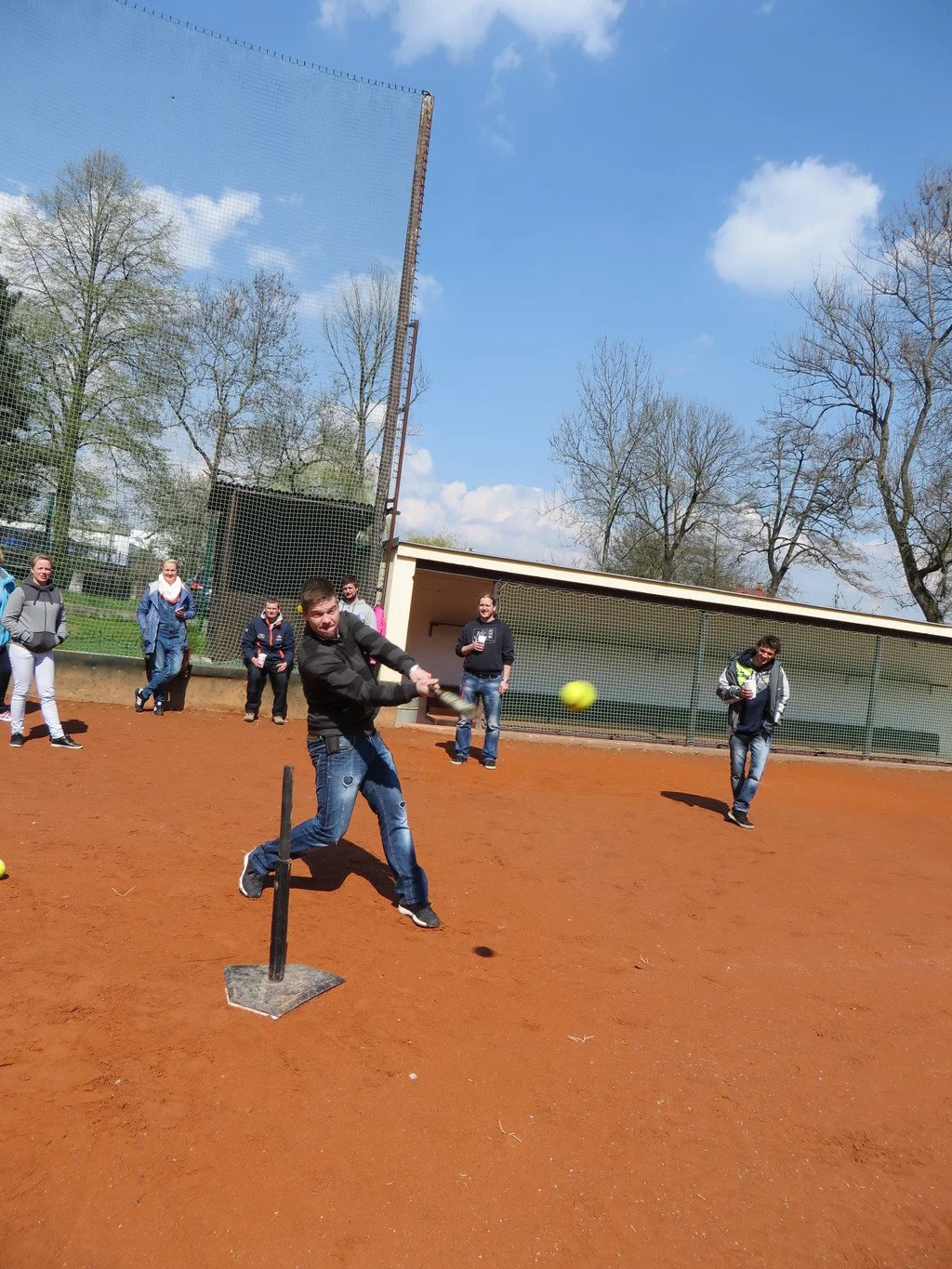 Muž odpaluje míček z odpalovacího stojanu při softballu