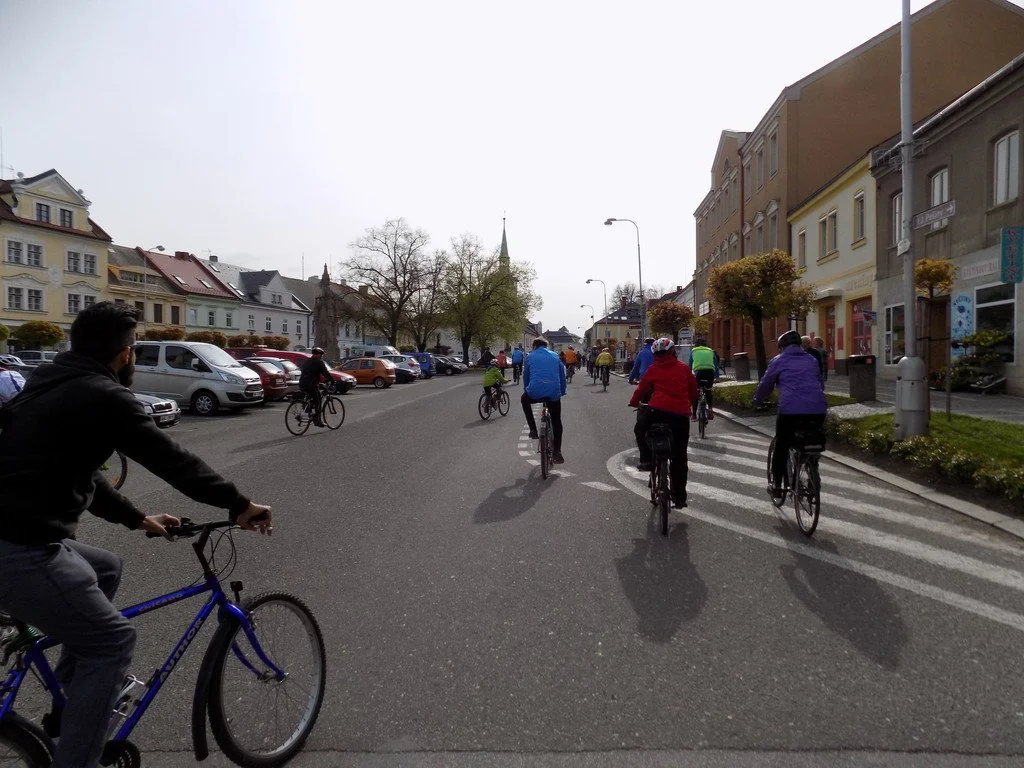 Skupina cyklistů projíždí ulicí města