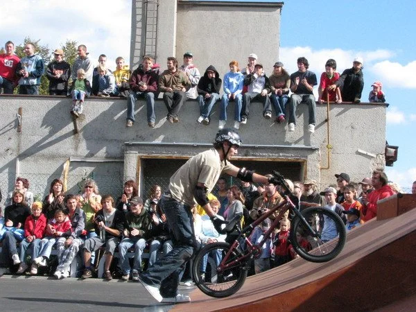 Cyklista předvádí trik na BMX kole před diváky na rampě