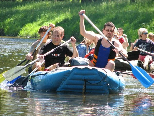 Skupina lidí sjíždí řeku na nafukovacím raftu