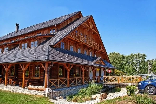 Dřevěná roubená restaurace s krytou terasou a zaparkovaným autem