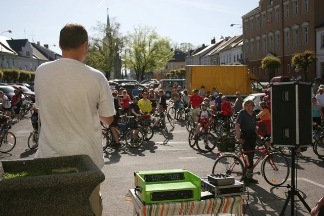 Muž zády k davu cyklistů obsluhuje reproduktory na náměstí