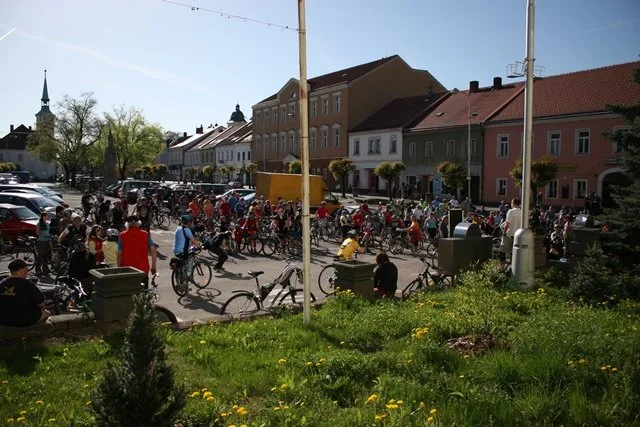Cyklisté shromáždění na náměstí s historickými domy