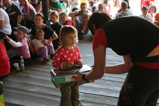 Dívka s krabicí od dortu na dřevěné podlaze mezi diváky