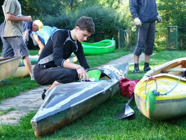 Muž připravuje kajak na trávě u cesty