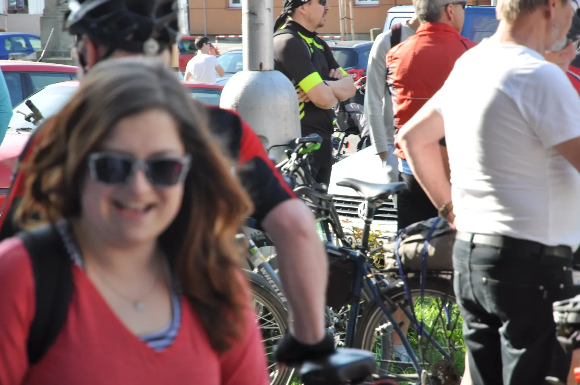 Usmívající se žena v popředí, v pozadí cyklisté s koly na ulici