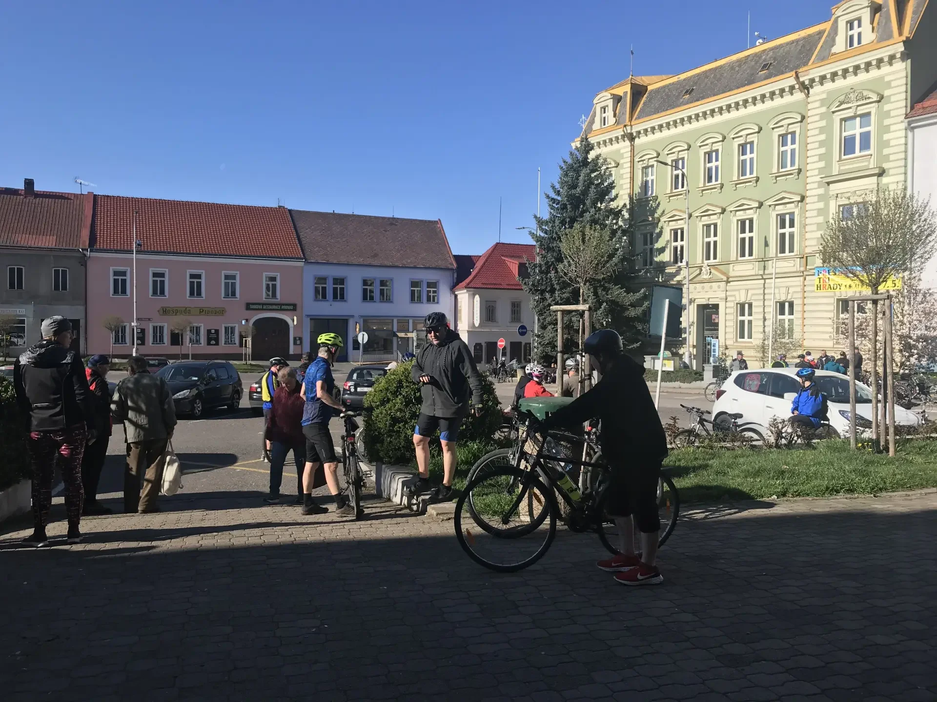 Cyklisté s koly se shromažďují na náměstí u zeleně
