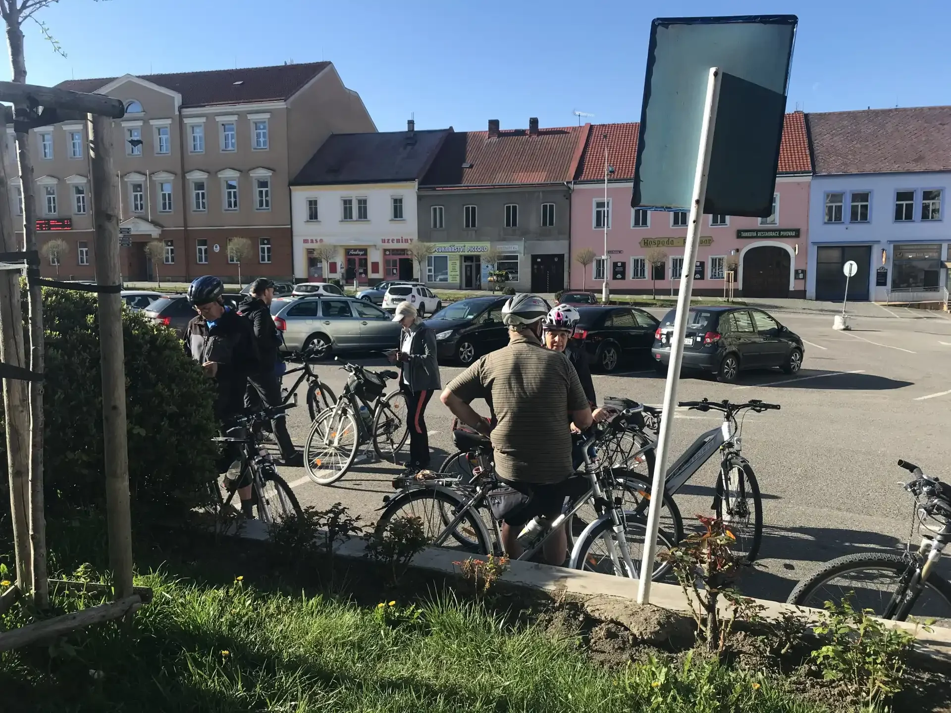 Skupina cyklistů s koly na chodníku před historickými domy