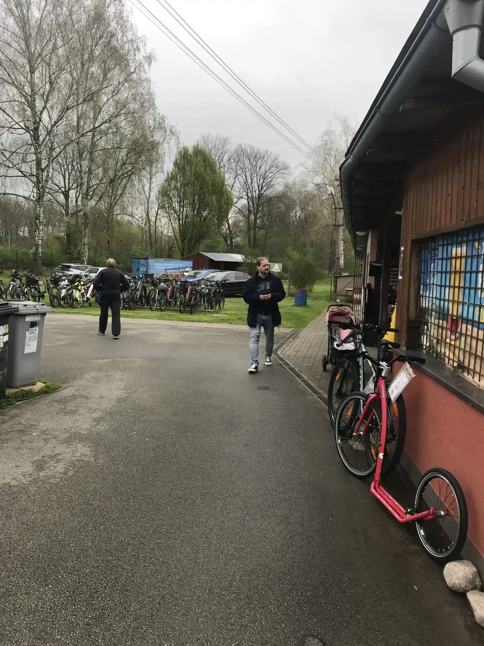 Cyklisté s koly u budovy s odstavenými bicykly na trávě
