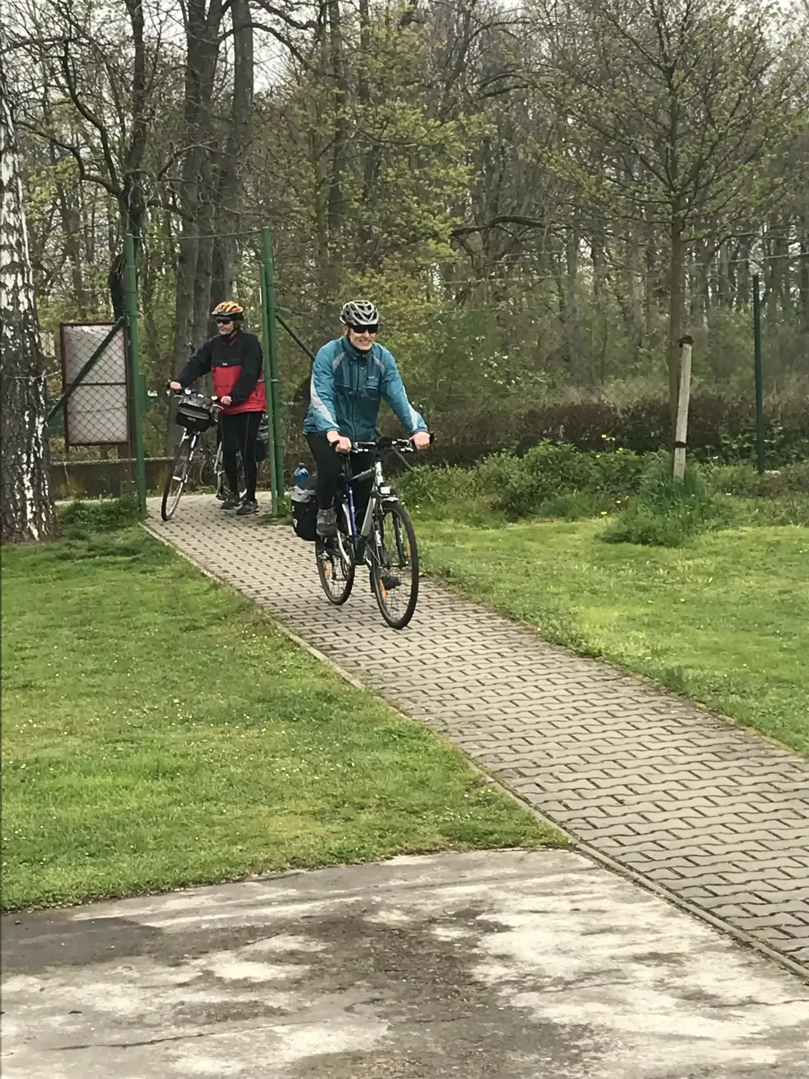 Dvě cyklistky v cyklistickém oblečení jedou po cyklostezce lesem