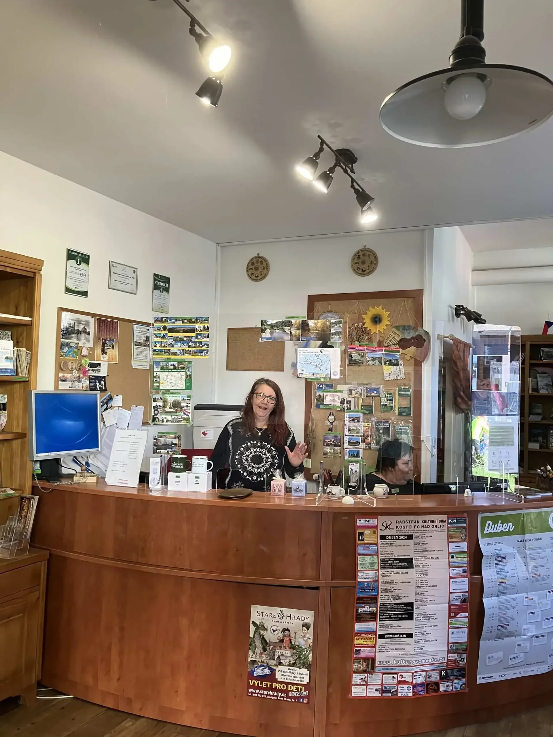 Žena za pultem informačního centra s turistickými materiály