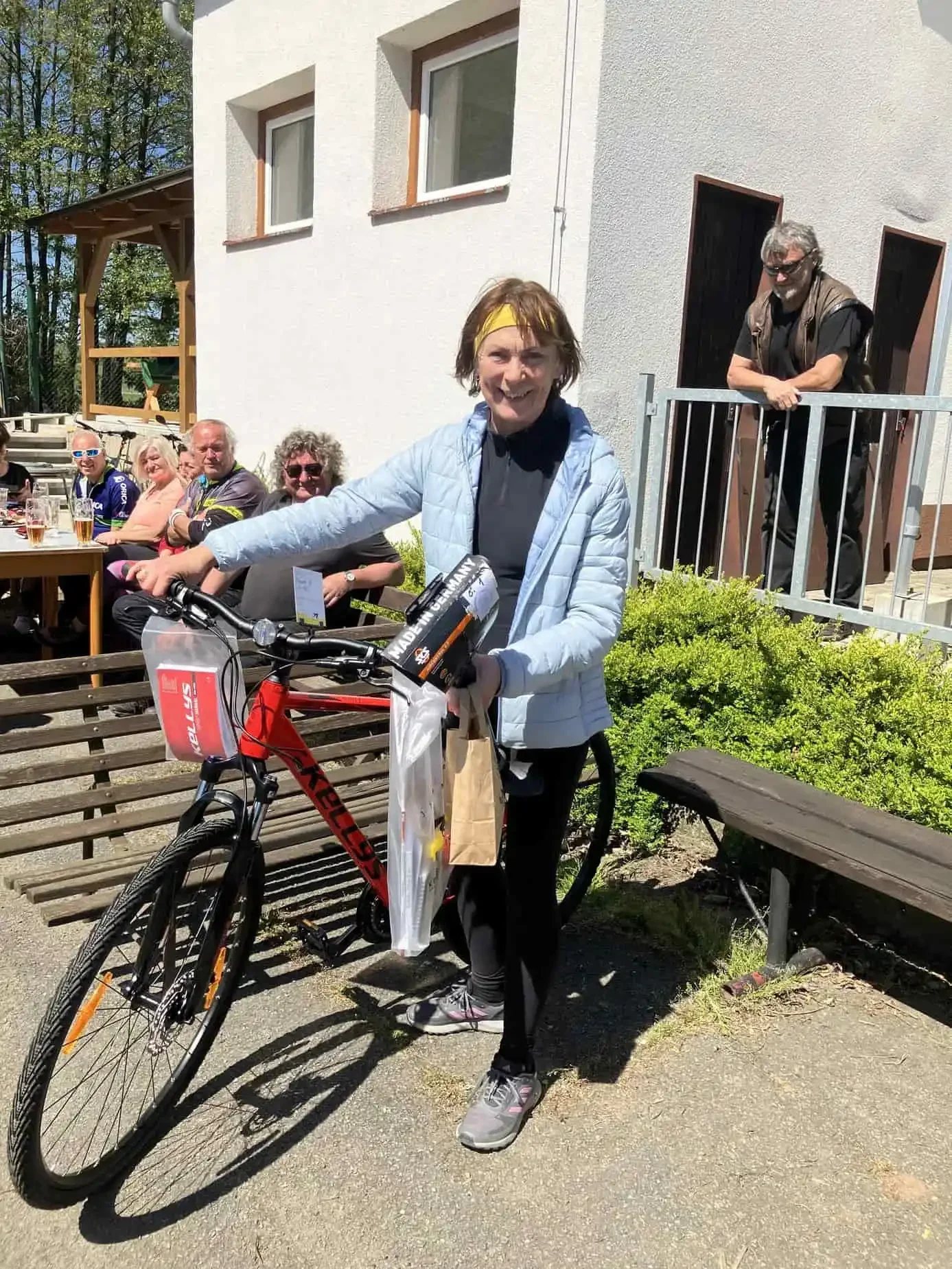 Žena se žlutou čelenkou u kola s cenou zabalenou v igelitu