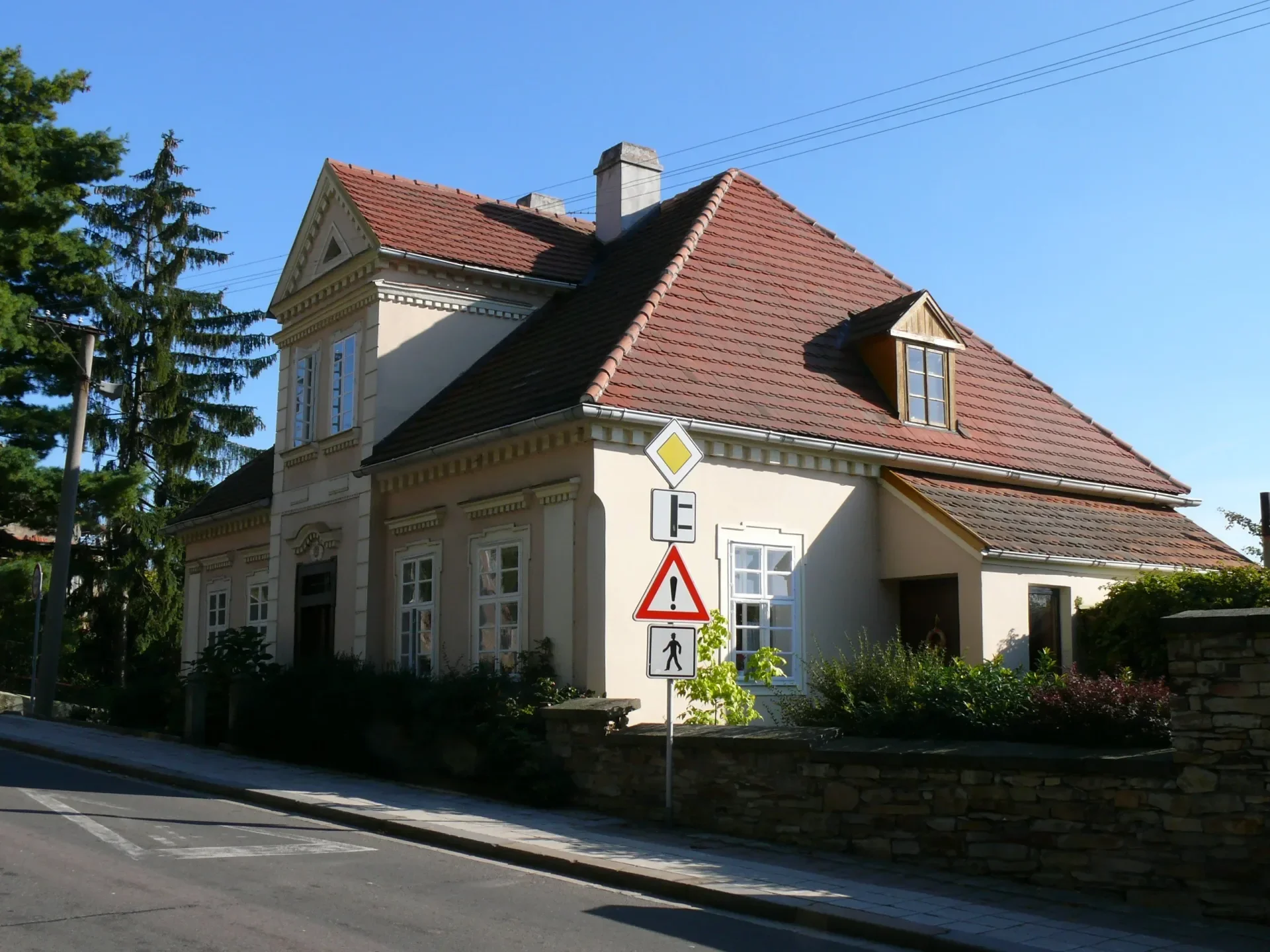 Vila s valbovou střechou a dopravní značkou u silnice
