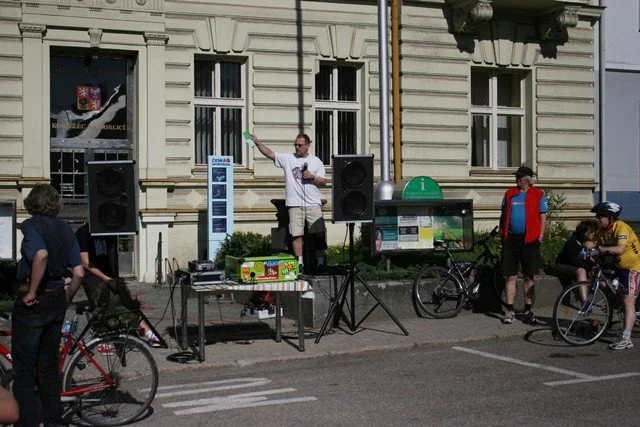 Chlapci na kolech projíždějí ulicí vesnice kolem stromu