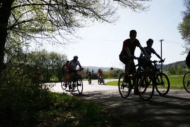 Skupina cyklistů projíždí lesní cestou během cyklosezóny
