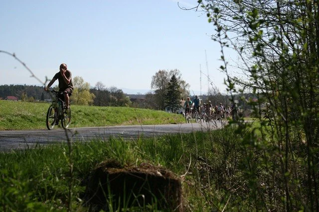 Cyklista na silnici, v dálce skupina dalších cyklistů