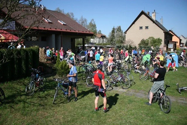 Skupina cyklistů odpočívá na trávníku před restaurací