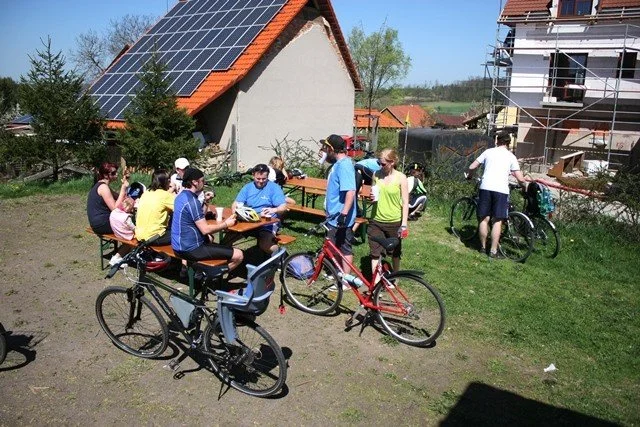 Lidé odpočívají u pikniku před domem se solárními panely na střeše