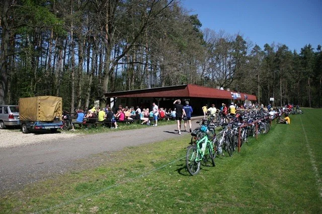 Cyklisté s koly před panelovými domy v cíli trasy